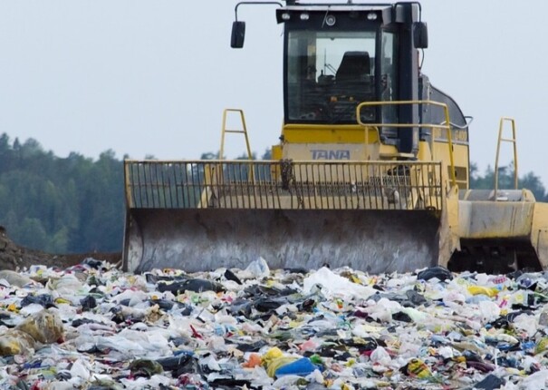 Tractor pushing garbage in a landfill.