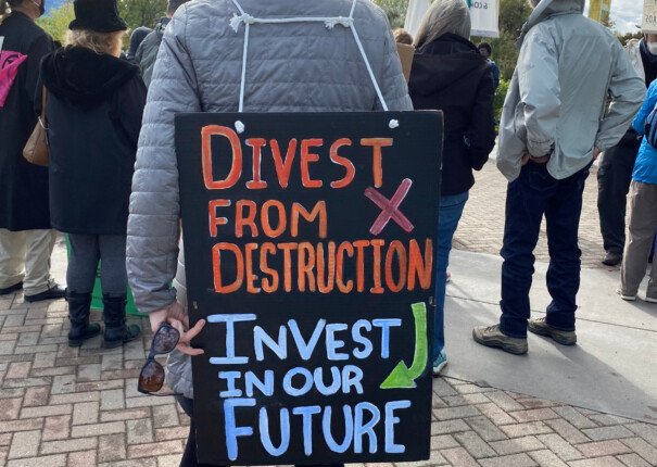 Climate activist in Sacramento holds a sign reading "Divest from destruction, Invest in our Future." Photo by The Climate Center.