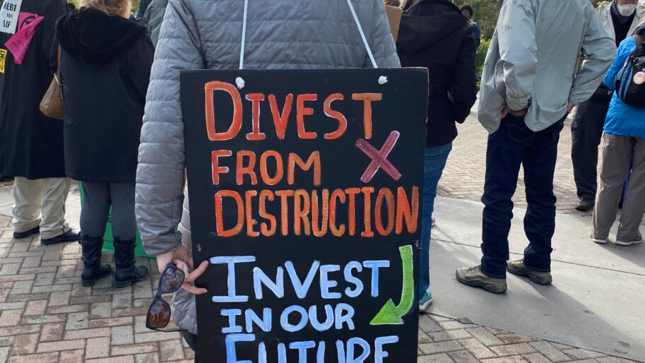 Climate activist in Sacramento holds a sign reading "Divest from destruction, Invest in our Future." Photo by The Climate Center.