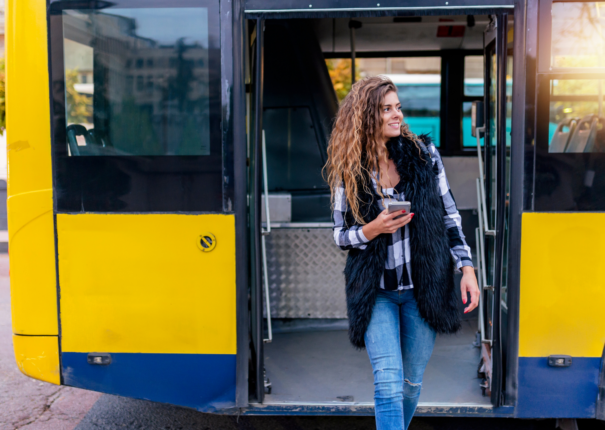A woman exiting yellow bus by Canva