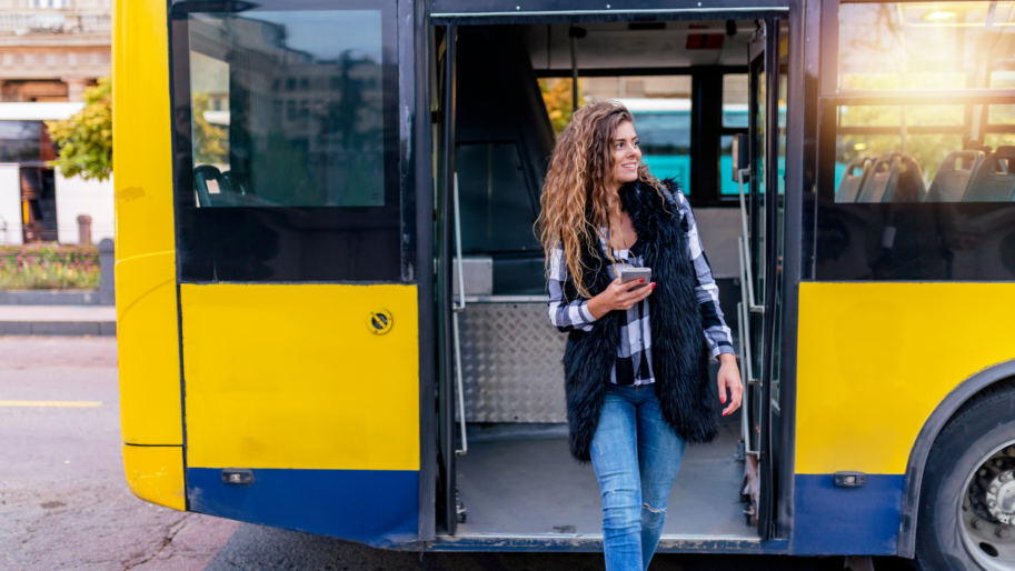 A woman exiting yellow bus by Canva